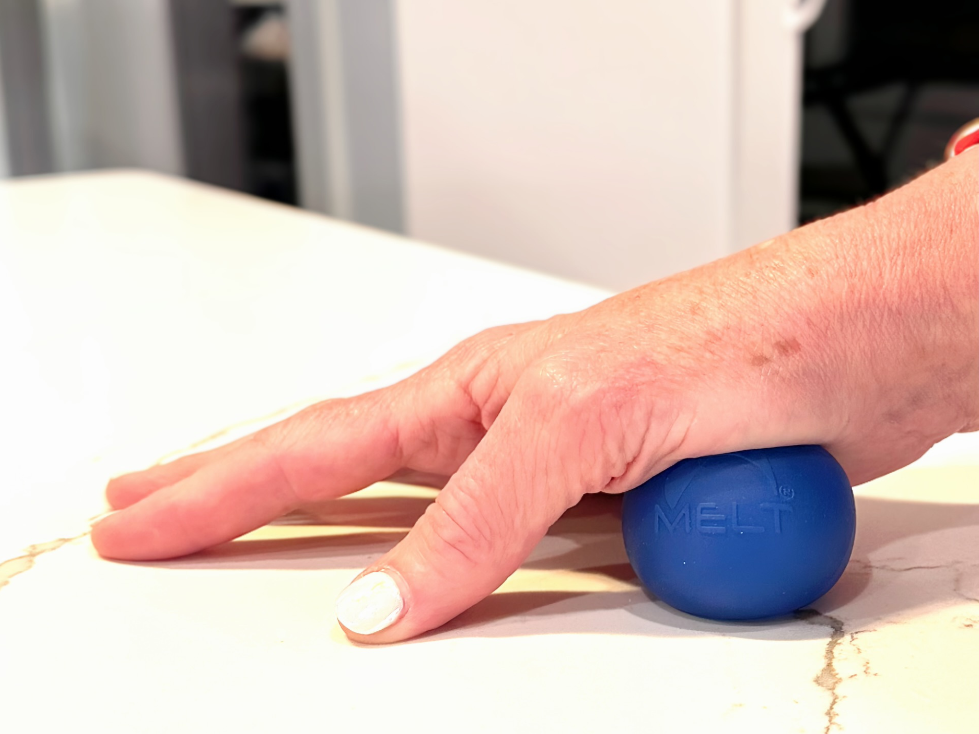 A MELT Method ball under a person’s hand on a countertop.